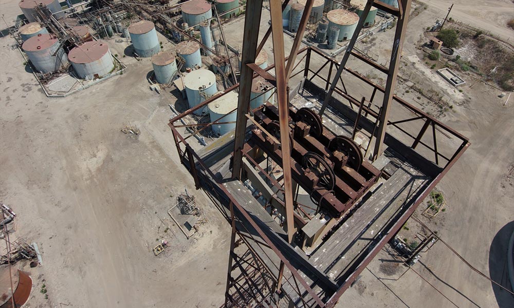Expert drone inspection services capturing the top structure of an old oil derrick during demolition for safety assessment